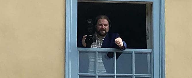 wedding photographer in window directing guests